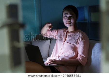 Photo of young Asian woman using laptop in the dark at midnight