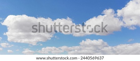 Expansive blue sky with white cumulus clouds, representing natural minimalism and serenity. Banner Royalty-Free Stock Photo #2440569637