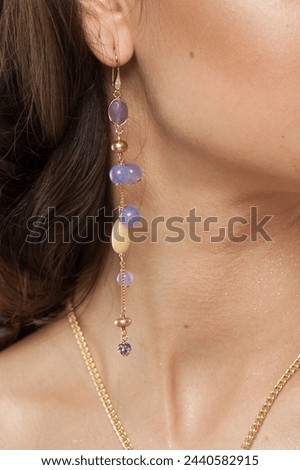Attractive jewelry model closeup. Golden Necklace and earring with blue and purple chalcedony stones Royalty-Free Stock Photo #2440582915