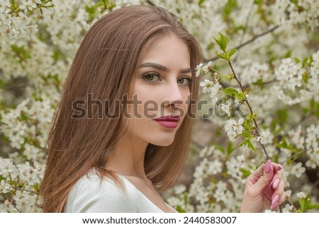 Joyful young woman with natural makeup and healthy long brown hair in blossom park outdoors. Natural female beauty portrait