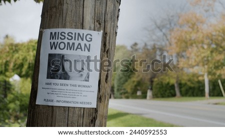 Poster for a missing young woman hangs on a pole near the road Royalty-Free Stock Photo #2440592553