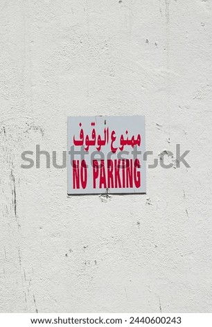 Bilingual No Parking Sign On Textured Wall