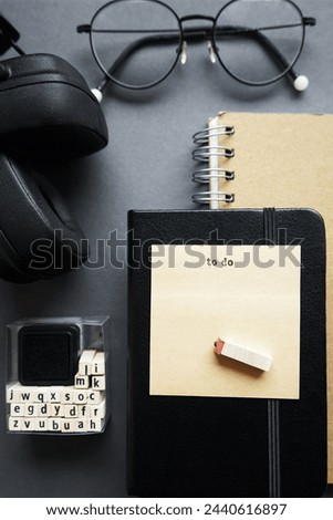 Notepads next to pen, sticky notes, glasses, smartphone and headphones on gray background