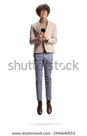 Hppy tall guy with glasses using a smartphone and jumping isolated on white background