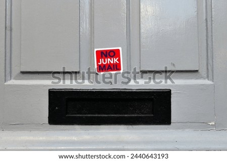 No Junk Mail sticker on a grey panelled wooden door above a black metal letterbox. Copy space available around the top portion of the picture. Royalty-Free Stock Photo #2440643193