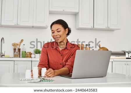 happy nutritionist looking at bottles with different medication during online consultation on laptop