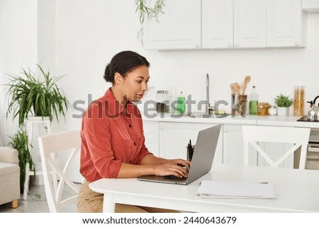 focused african american nutritionist using laptop while working remotely from her modern kitchen
