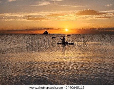 Happy Woman Silhouette Rowing in a kayak at sunset