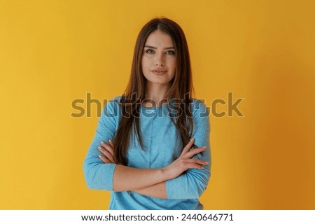 Confident look, portrait. Young woman is against yellow background.