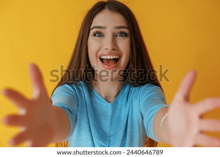 Screaming of shock or anticipation, hands gesture. Young woman is against yellow background.