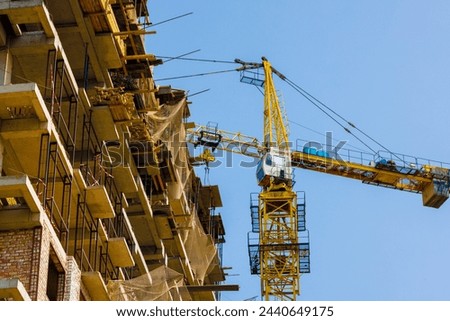 construction site and yellow crane on the blue sky background, view from below