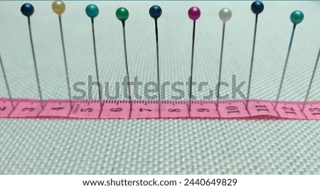 sewing needles and pins of different colors, ruler on white cloth background