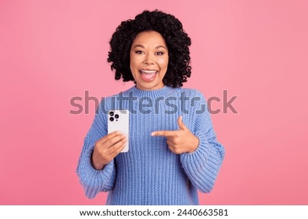 Photo portrait of lovely young lady point gadget sales shopping dressed stylish blue knitwear garment isolated on pink color background