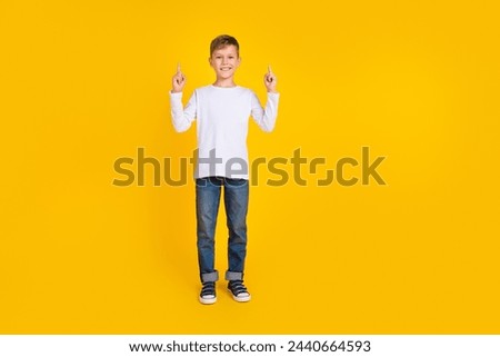 Full length photo of excited funky kid dressed white shirt showing two fingers up empty space isolated yellow color background