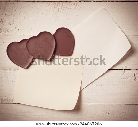 Chocolate heart with note paper on the wooden background,vintage color toned image
