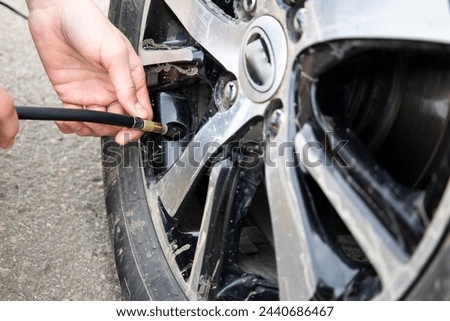 Man checking air pressure and filling air in the tires of car. Concept picture