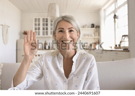 Smiling middle-aged woman look at camera make video call, start personal conversation with family living abroad use modern application, spend leisure at home. Wireless technology, videocall app usage Royalty-Free Stock Photo #2440691607