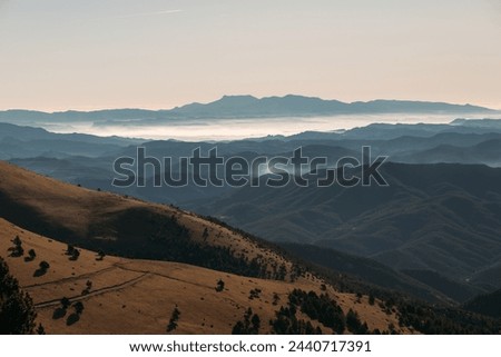 Shadowy Mountain Slopes Leading into Misty Valleys at Dawn Royalty-Free Stock Photo #2440717391