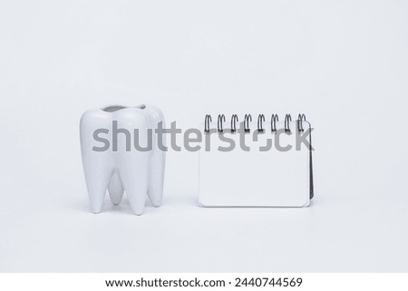 white tooth and notepad on a white background. dentistry concept