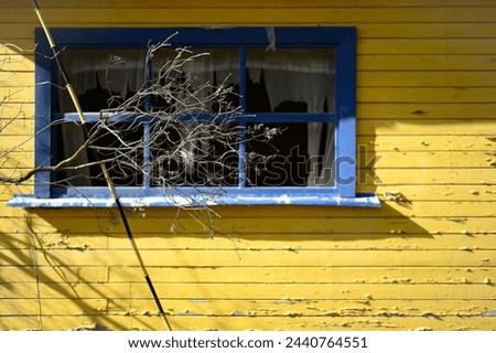 Abandoned house in bright yellow and blue colors. Empty window without glass