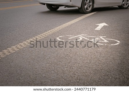 A vehicle crossing a bicycle lane marked with painted bike and directional arrow symbols.