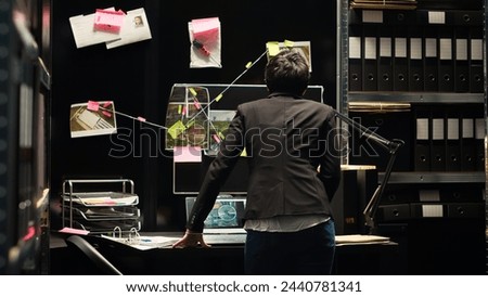 Police investigator looking at clues board in incident room, analyzing forensic evidence to uncover new investigation details. Woman detective reviewing intelligence, secret mission. Royalty-Free Stock Photo #2440781341