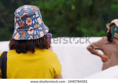 Young girl having a good time with her mother on public park, taking picture using mobile phone and happy each other
