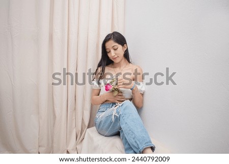Horizontal image of a beautiful young slim Caucasian woman holding flowers in her hand