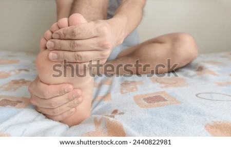 A Person massaging their foot due to pain in the sole, arch and toes. Space for text on the right.