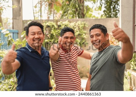 Group of joyful asian adult friends showing thumbs up, signifying approval, success or happiness. Royalty-Free Stock Photo #2440861363