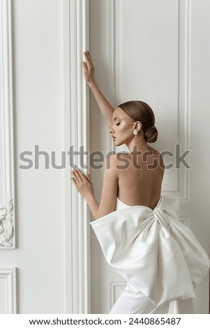A slim and beautiful lady of European descent captured in a series of photos wearing a stunning open-back white dress, exuding sophistication and charm in a chic studio setting