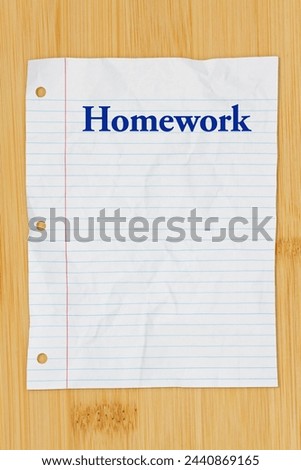  Homework message on crumpled lined rule paper on wood desk Royalty-Free Stock Photo #2440869165