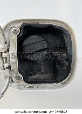  The close up picture dirty gas cap of a white sedan car