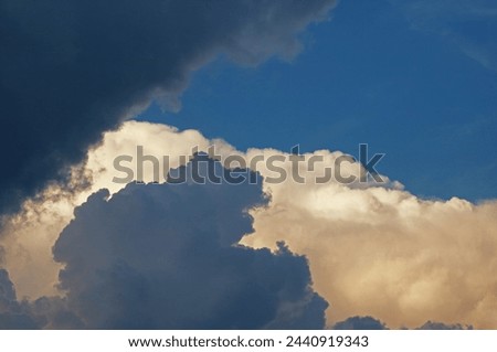 CONTRASTING BLUEISH GREY AND PINK GLOWING CLOUDS IN A BLUE SKY Royalty-Free Stock Photo #2440919343