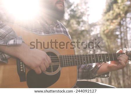 A folk country musician playing his guitar.  Royalty-Free Stock Photo #244092127