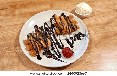 Churros with chocolate sauce. A snack or side dish made from fried dough, usually choux. Churros are a traditional dish in Spain and Portugal.

