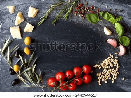 Ingredients for cooking italian pasta shot on dark stone background. anorama of Italian cuisine with space for text. The composition includes olives, cherry tomatoes, pine nuts, basil, rosemary, flour