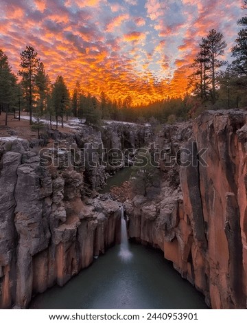  picture of a river and a waterfall under the mountain, and a sky containing clouds with the orange color of the sun, a wonderful view