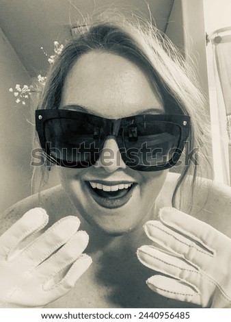Black and white sultry model posing in sunglasses, flowers in her hair Royalty-Free Stock Photo #2440956485