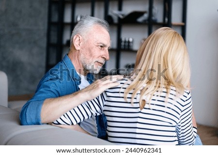 Elderly man give support to woman in difficult situation. Sitting on couch at home and carrying about partner, listening carefully and understanding feelings of friend or spouse Royalty-Free Stock Photo #2440962341