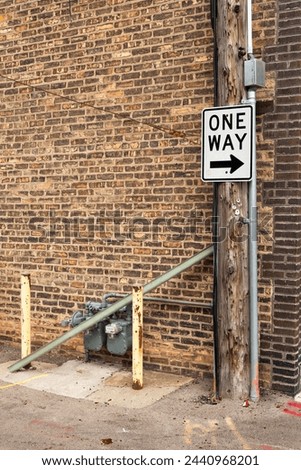 One way sign and brick wall in back alley.