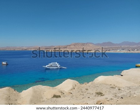 Red Sea  lagune with mountains on the horizon and turquoise water, white yacht  and sandy bank.