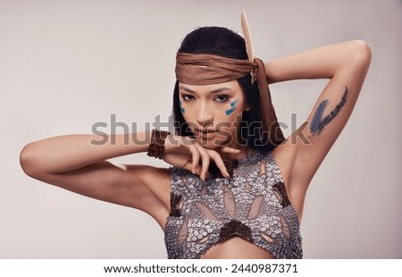 Portrait, beauty and Native American woman in studio with warrior makeup, confidence and tribe style. Indigenous fashion, face paint or girl in First Nations clothes on white background with culture