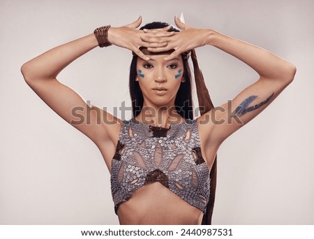 Portrait, woman and Native American style in studio with warrior makeup, confidence and tribe culture. Indigenous fashion, face paint or girl in First Nations clothes on white background with feather