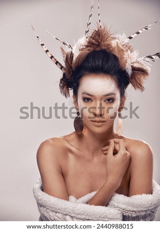 Model, portrait and native american headdress in studio with feather, hair and beauty with culture cosmetics. Woman, face and indigenous make up or art and elegant fashion or cloth on grey background