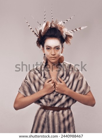 Woman, portrait and Native American with fashion for culture, tradition or art on a gray studio background. Female person with feather, face paint or stylish tribal clothing of goddess in beauty