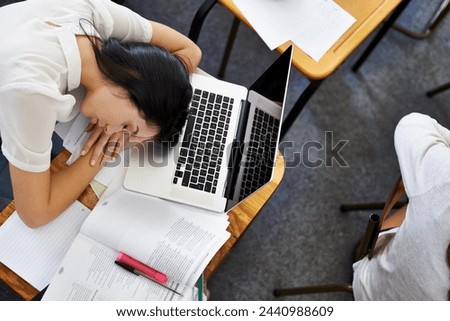 Laptop, education and woman student sleeping on desk in class with exhaustion or fatigue from above. Computer, burnout or tired and young person asleep in school classroom with books for study Royalty-Free Stock Photo #2440988609