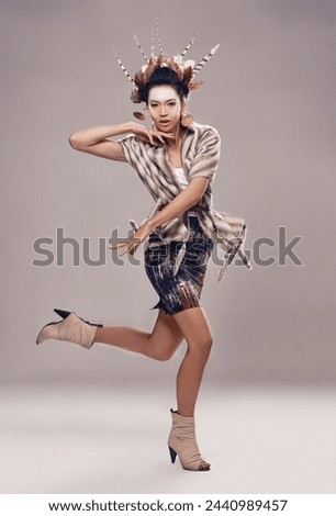 Woman, dancer and portrait for culture fashion in studio, feathers and tribal make up in trendy clothes. Native american, model and face in indigenous cosmetics and accessories on grey background