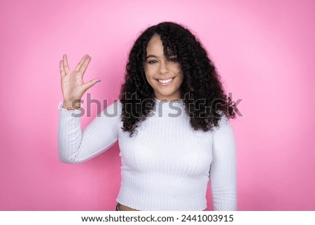 African american woman wearing casual sweater over pink background doing star trek freak symbol