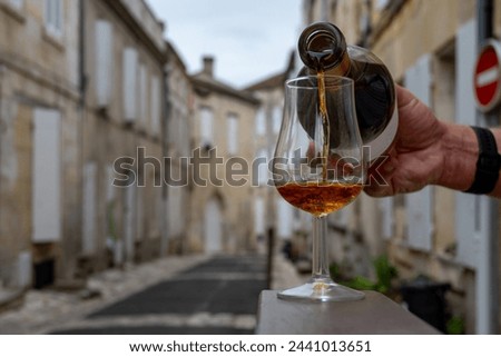 Tasting of aged in barrels cognac alcohol drink and view on old streets and houses in town Cognac, Grand Champagne, Charente, strong spirits distillation industry, France Royalty-Free Stock Photo #2441013651